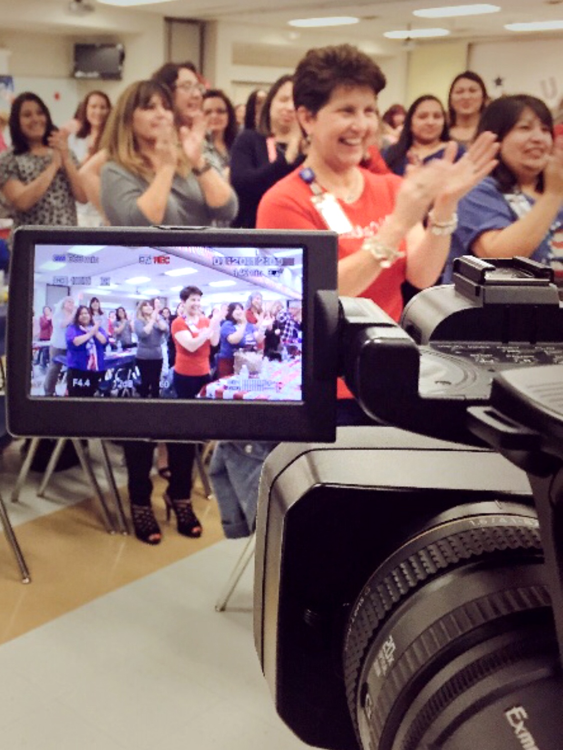 Large female audience standing and clapping with camera in foreground