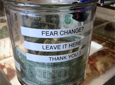 Glass change jar with "Fear Change? Leave it Here" label