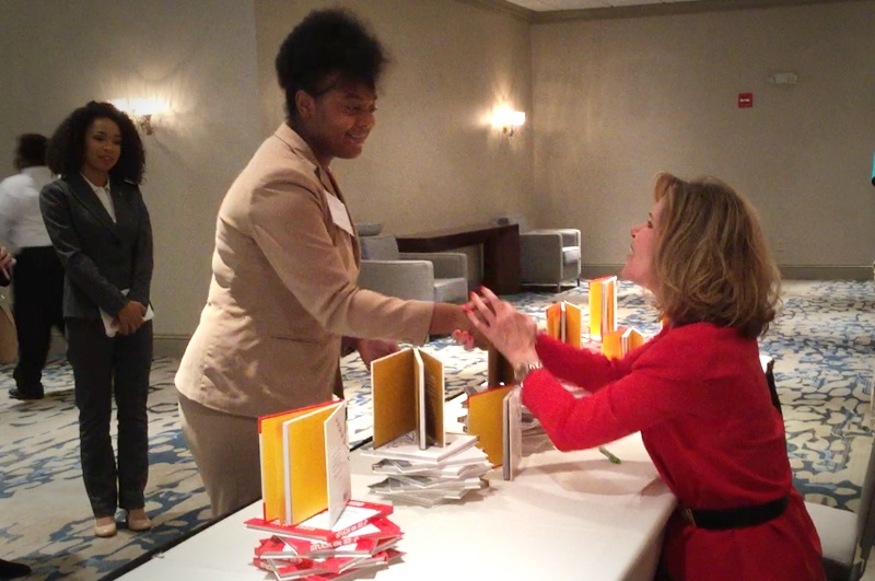 Keynote speaker Vicki Hitzges at book signing shakes hands with woman